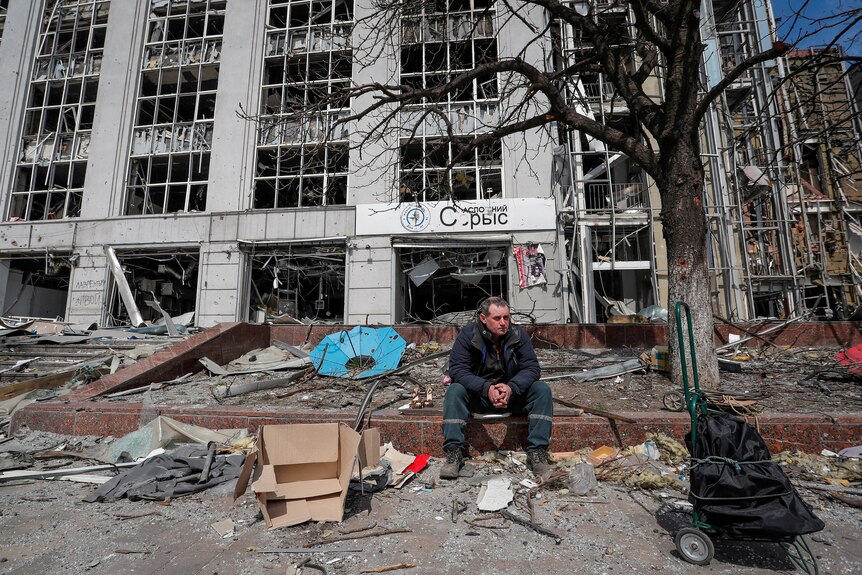 Man sits among rubble on a Mariupol street