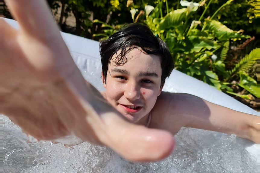 Zane Mellor in a pool reaches for the camera.