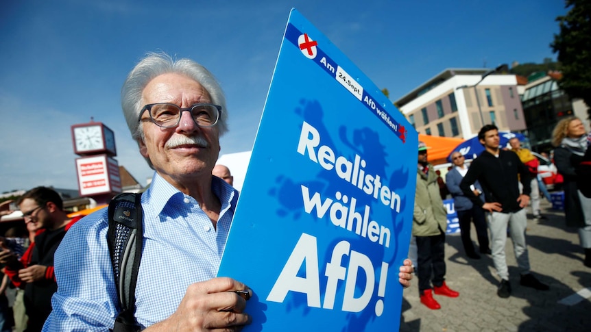 A man holds an anti-immigration party Alternative fuer Deutschland AfD placard