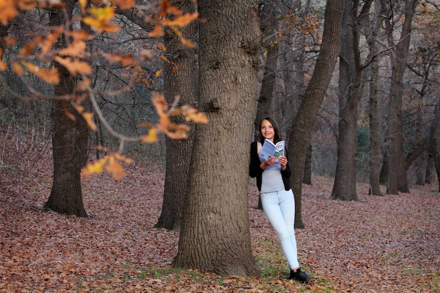 Young girl holding book in the forest