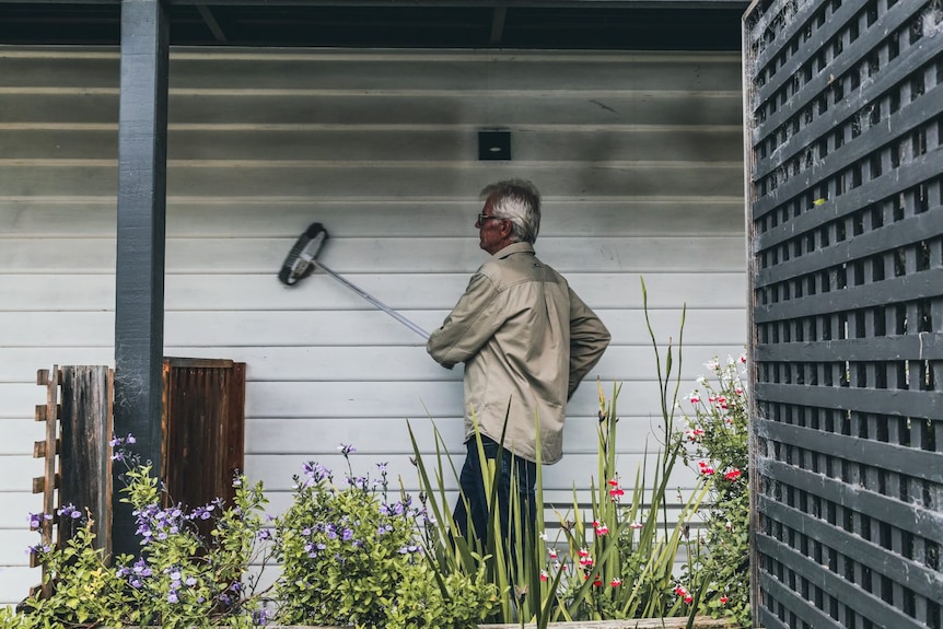 Robert Richards brushes dust from his weatherboard home