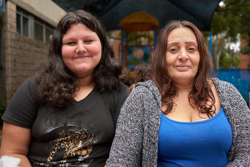 Annette and her teenage daughter Hannah pictured outside a community centre, smiling slightly.