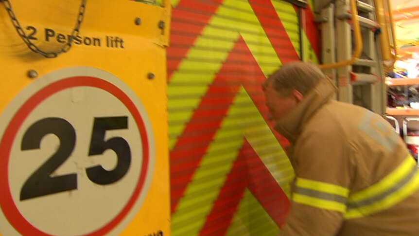 The back of a fire truck with a 25 sign on it and a man standing behind it