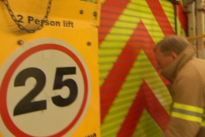 The back of a fire truck with a 25 sign on it and a man standing behind it