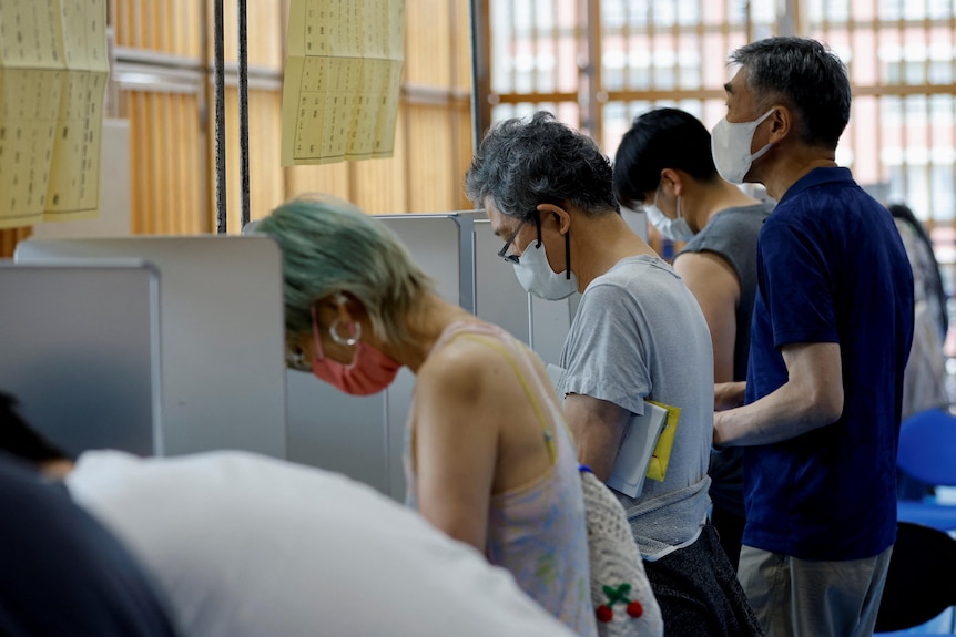 voters in face masks cast their ballots for the Japanese upper house election in a room