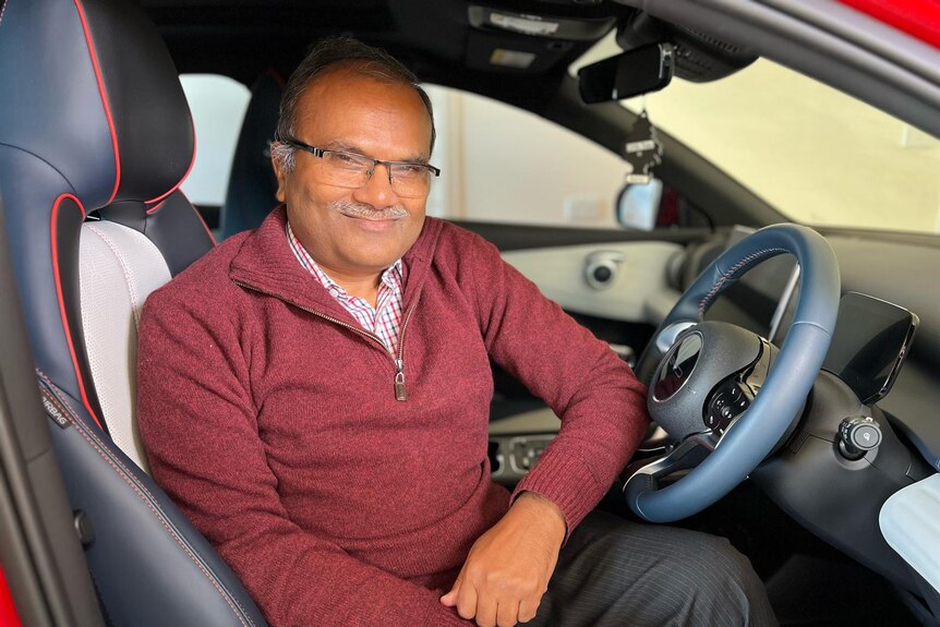 A man sitting in the driver's seat of a car and smiling