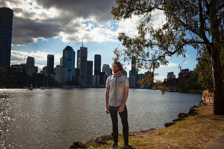 Mark McVeigh stands beside the Brisbane River