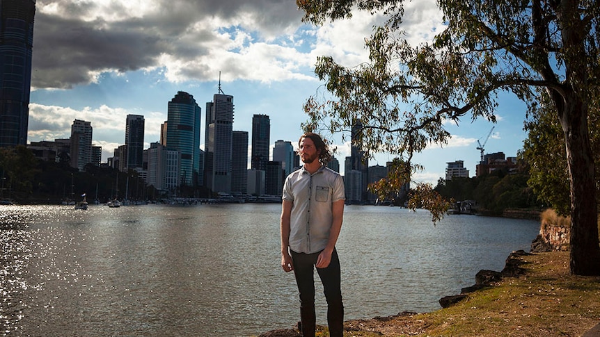 Mark McVeigh stands beside the Brisbane River