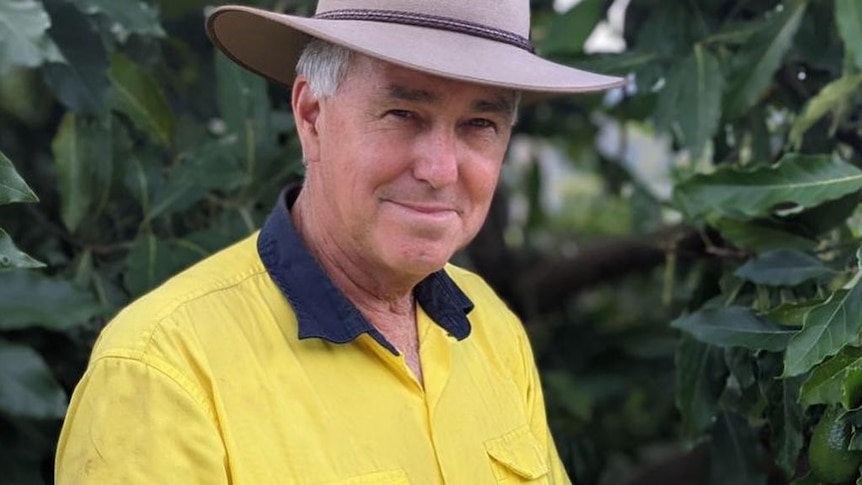 Man stands in front of tree in hi vis with hat