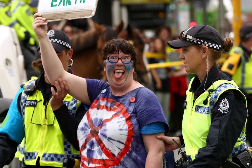 An Extinction Rebellion protester being arrested by police holding up a protest sign.