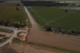 A drone shot of a flooded road with water being diverted down a gravel road.