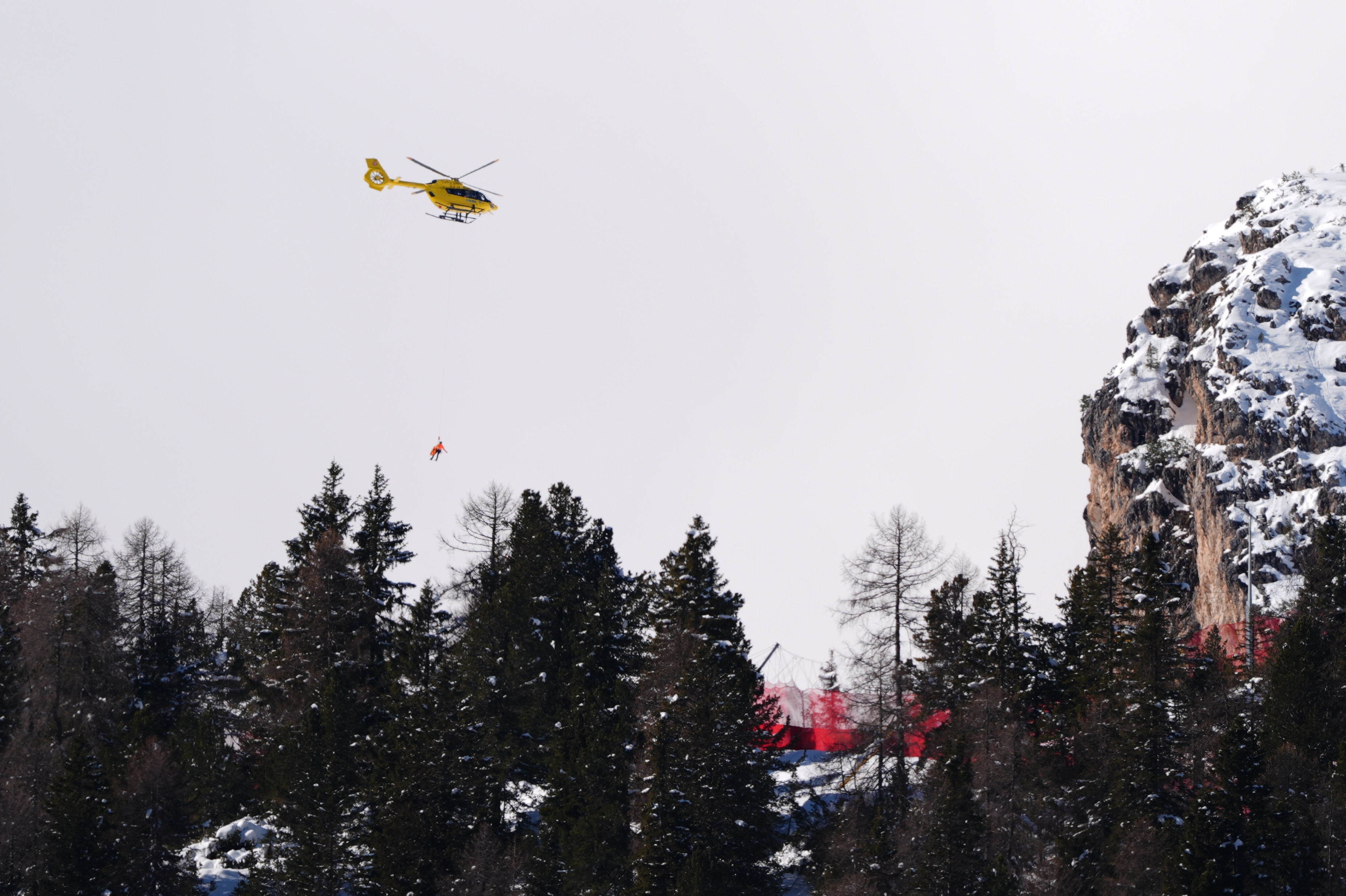 Un helicóptero sobrevuela los árboles con una camilla colgando debajo