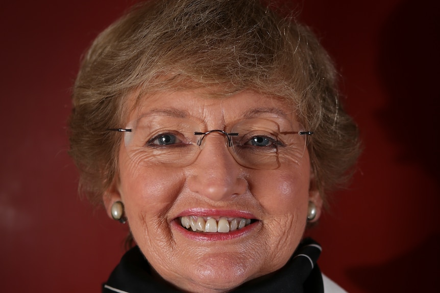 A smiling, middle-aged woman wearing glasses.