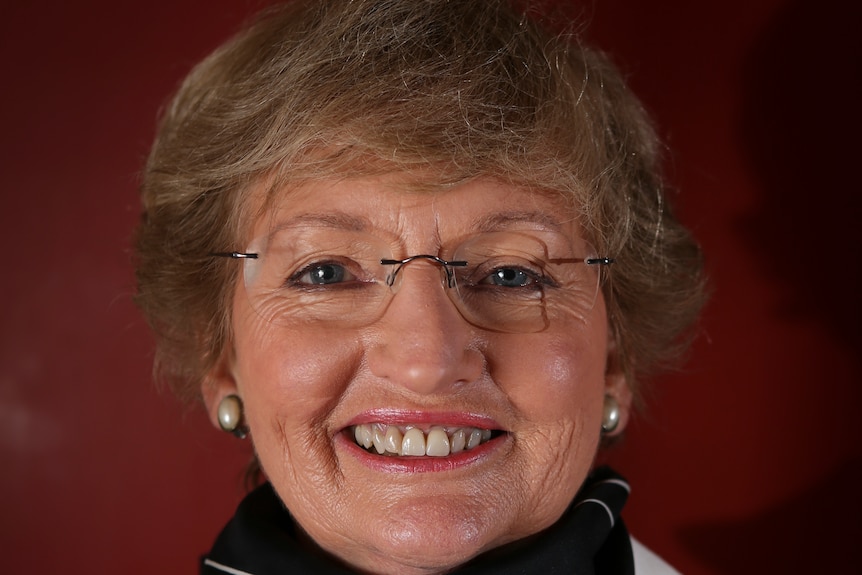 A smiling, middle-aged woman wearing glasses.