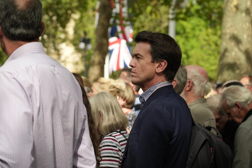 Rowland standing in crowd on London street.