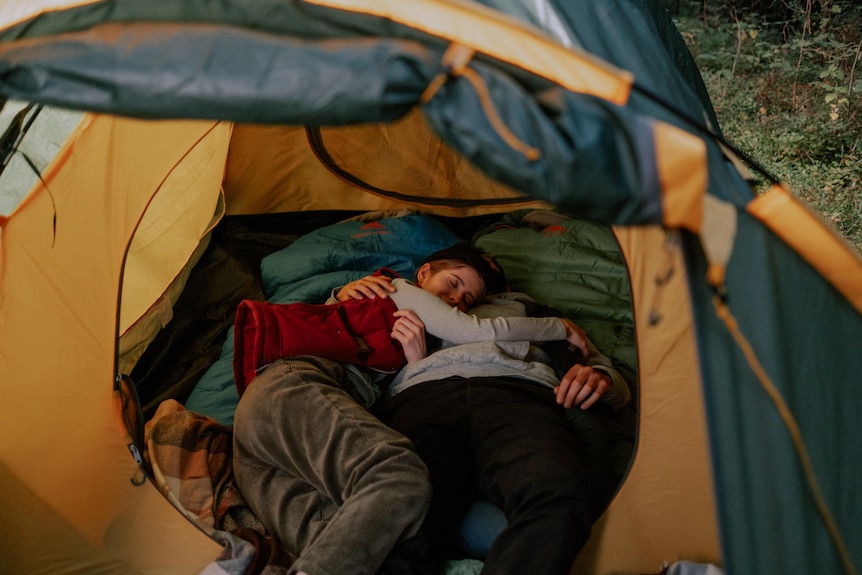 A couple embrace in a tent.