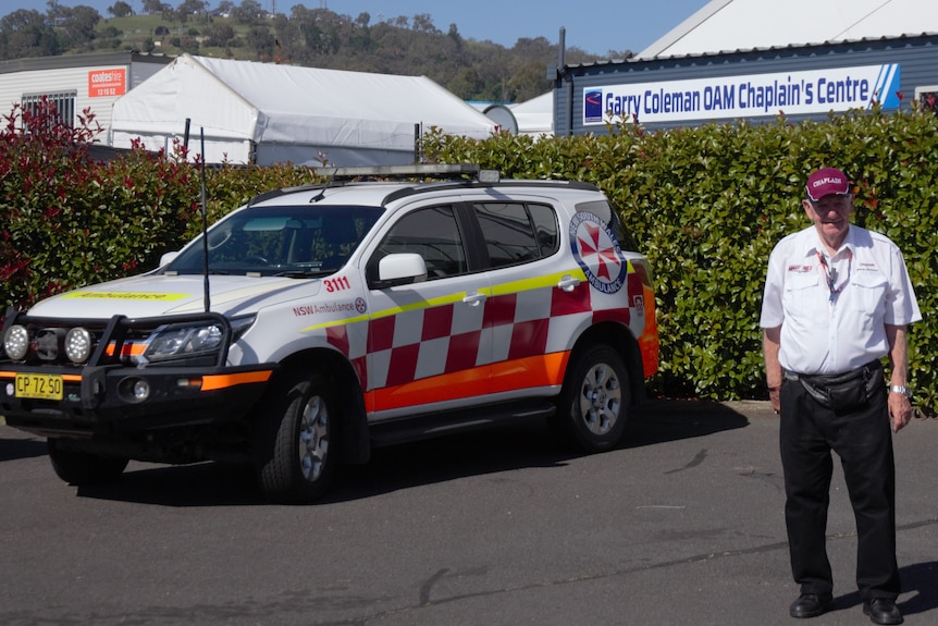 80-year old Rev. Garry Coleman standing in front of an ambulance and the blue support centre named after him