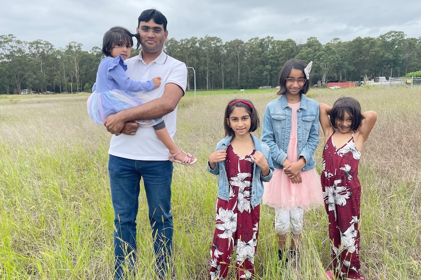 A man stands in a field with 4 children