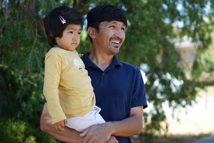 Ali Rahmani and his daughter look into the distance smiling