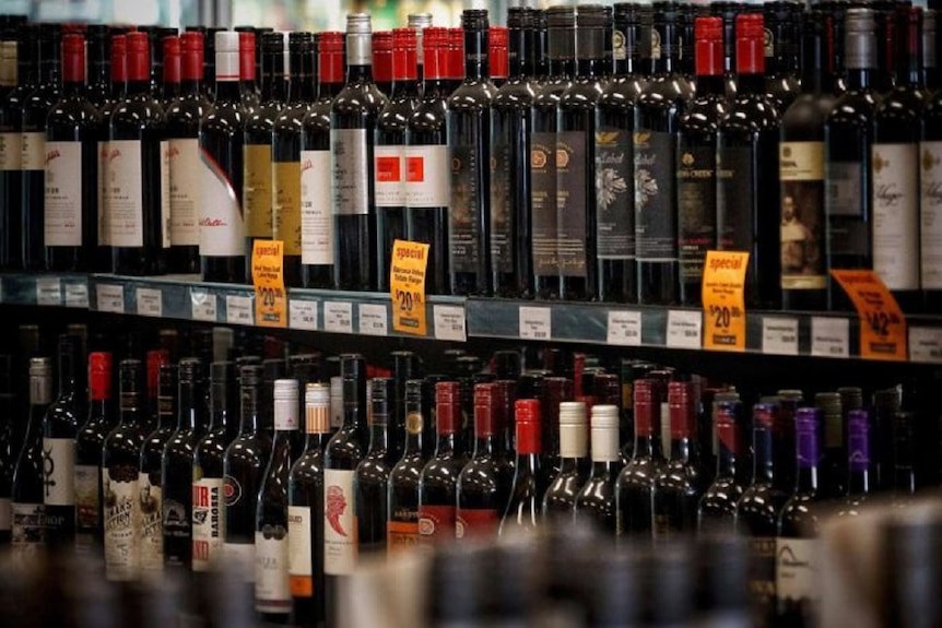 Many bottles of red wine on shelf in bottle shop
