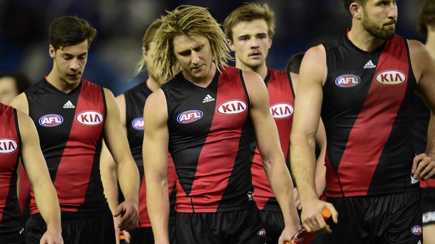 Dyson heppell leads Essendon players off the field after their loss to Western Bulldogs