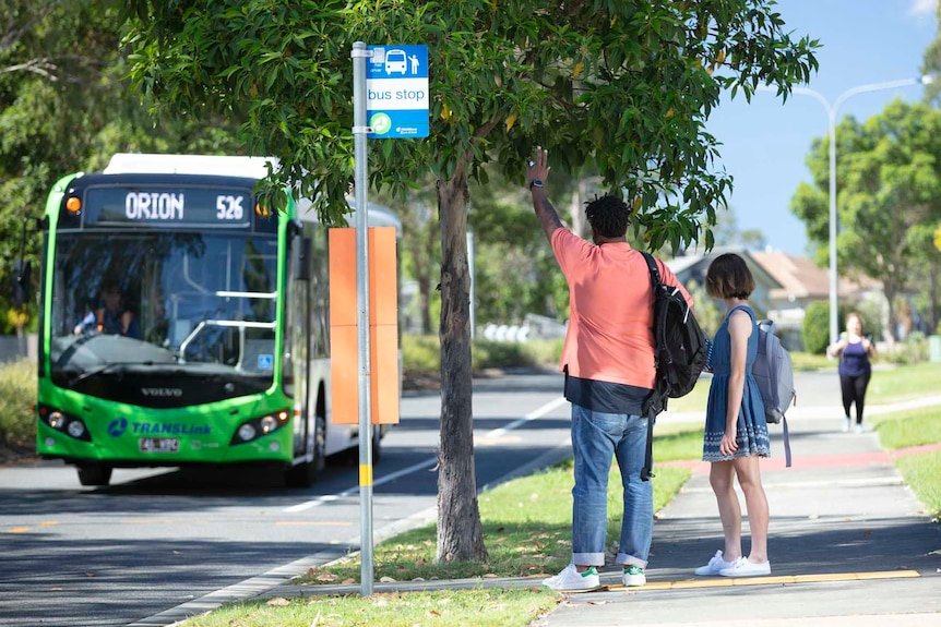 Two people hailing a bus on street