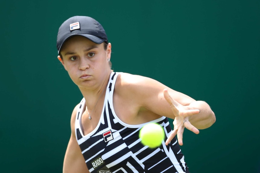 Ash Barty puffs out her cheeks and stares intently at the ball as she prepares to hit it.