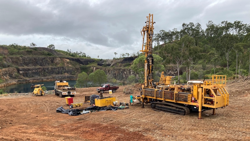 Drilling machinery on dirt near ar mining pit.