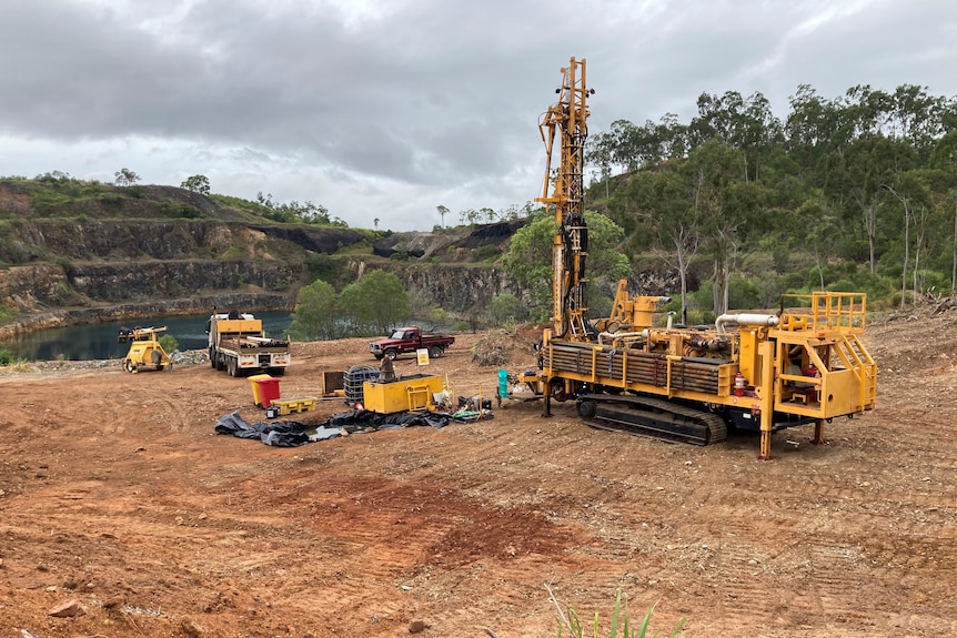 Drilling machinery on dirt near ar mining pit.