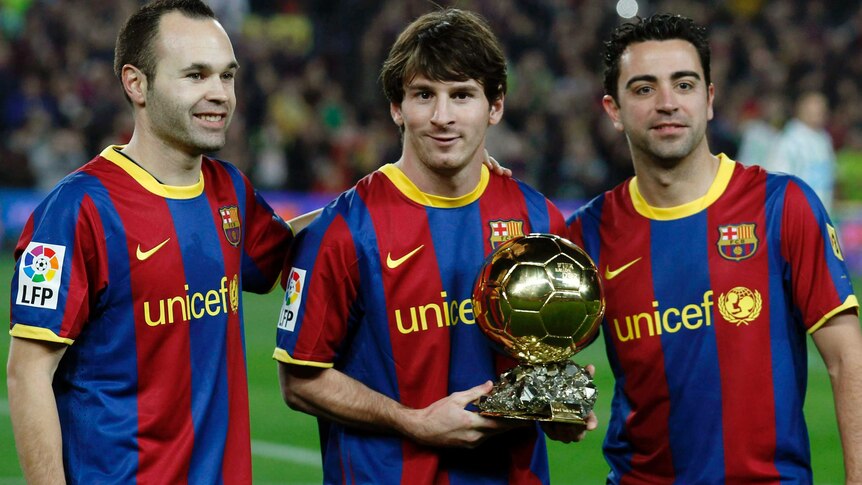 Lionel Messi shows off one of his five Ballon d'Or trophies alongside Andres Iniesta and Xavi