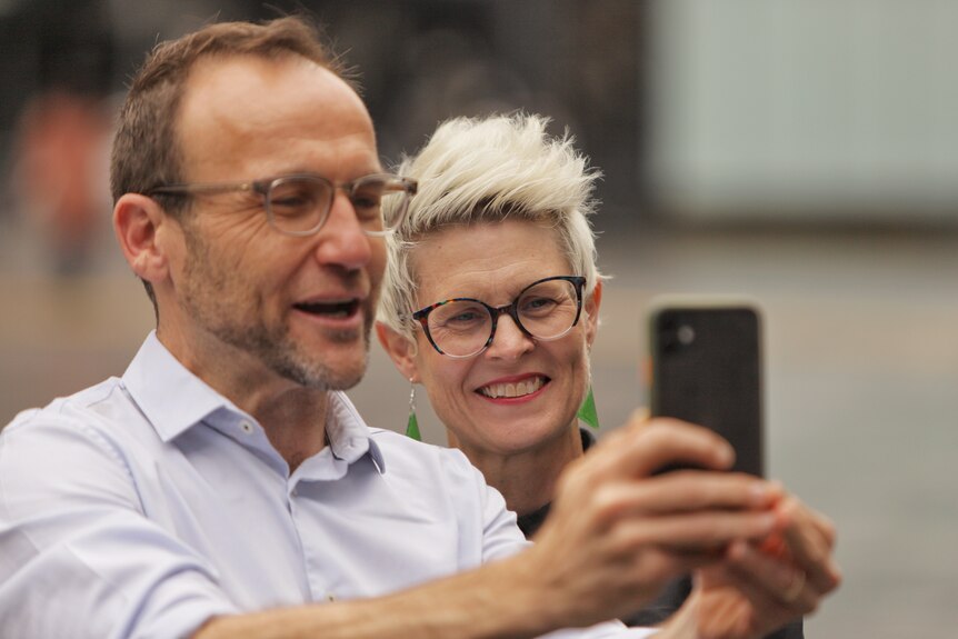 Penny and Adam smile while taking a selfie 