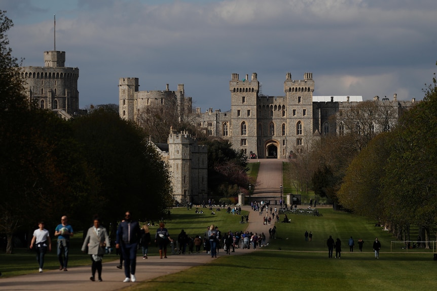 A line of people walk along the Long Walk - a long wide path in front of Windsor Castle.