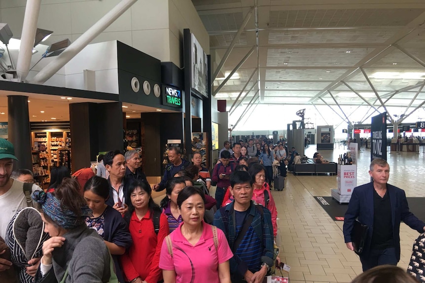 Long queue of people waiting to go through Border Force passport checks at Brisbane Airport on April