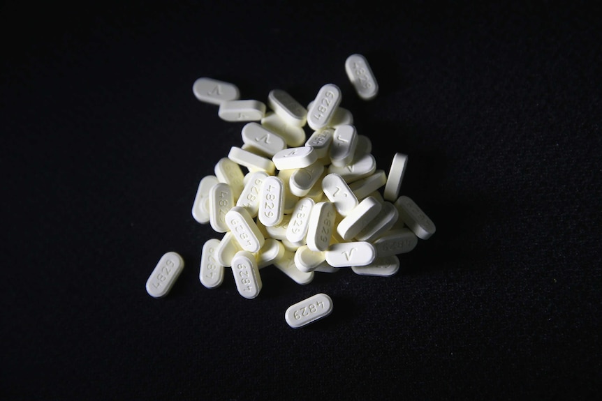 White prescription pills on a black background.