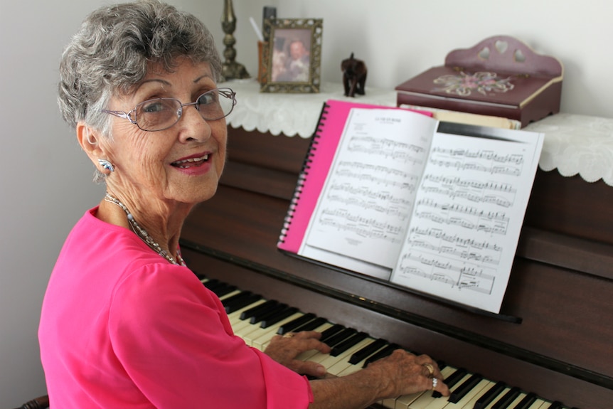 Older woman smiling at the piano.