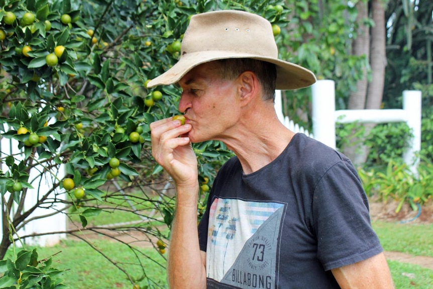 A man eats a kumquat on the side of a street