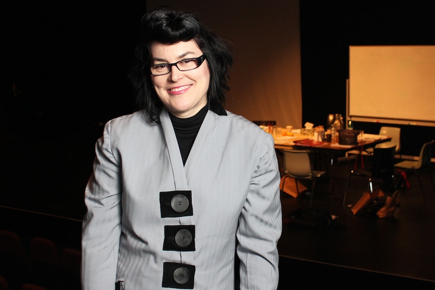 playwright Alana Valentine smiling and standing inside a dark theatre