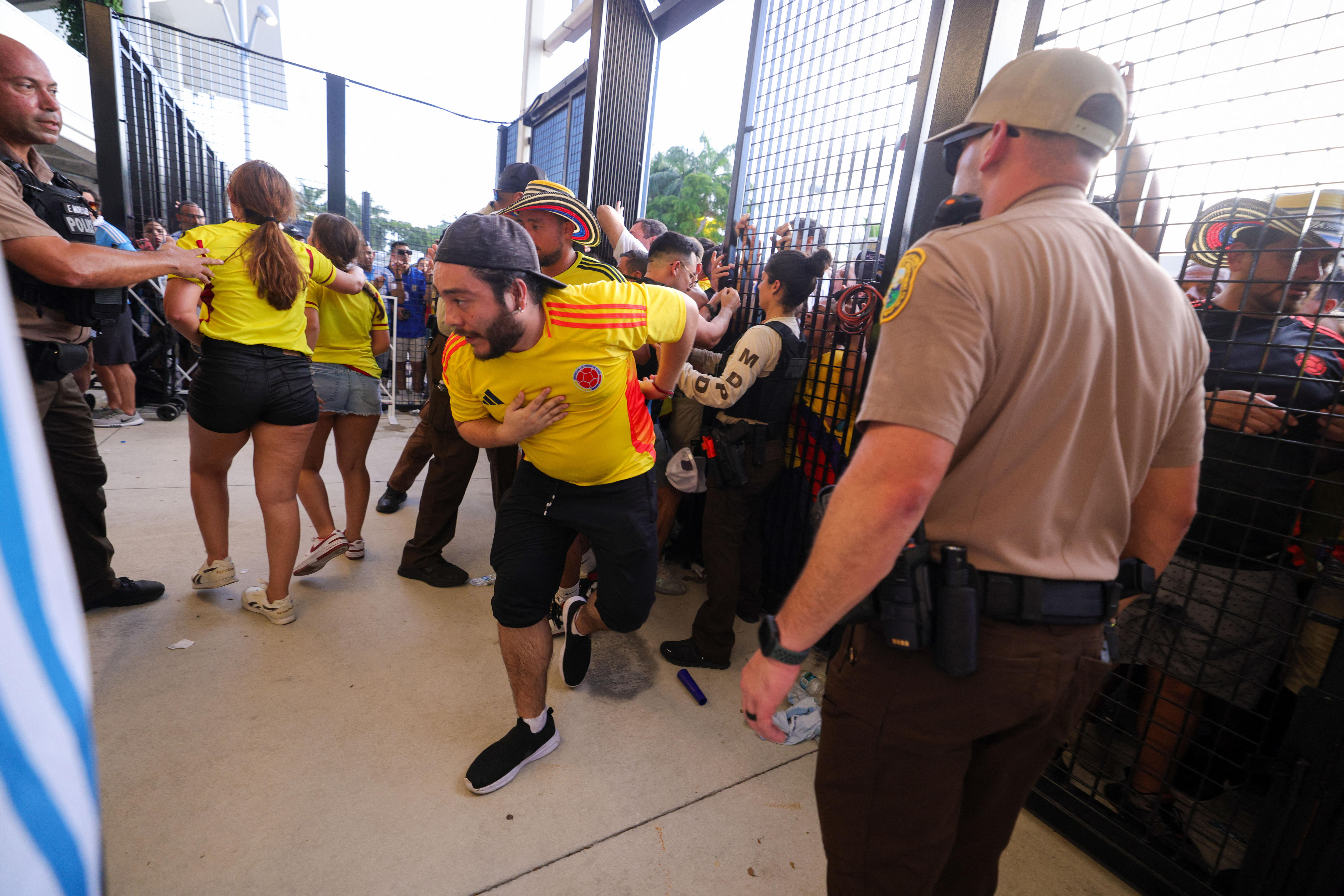 Fans rush towards the gates before entering a stadium as security tries to maintain order