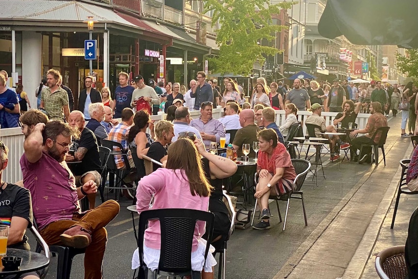 People sitting on chairs and tables on a city street