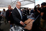 Scott Morrison cooks sausages on a barbecue surrounded by media