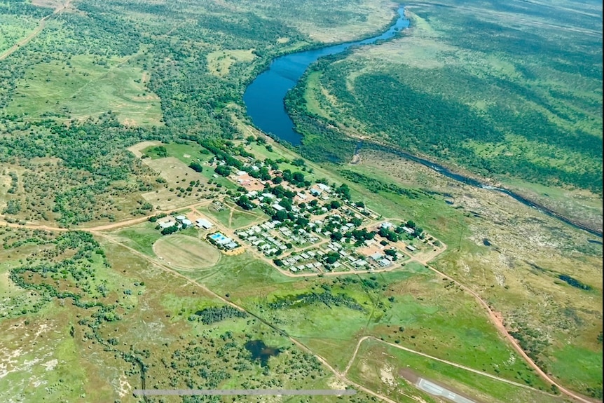 A lush green landscape with a small community clustered on a riverbank