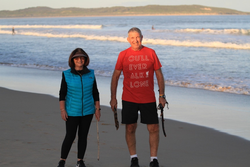 A woman and man stand on a beach.