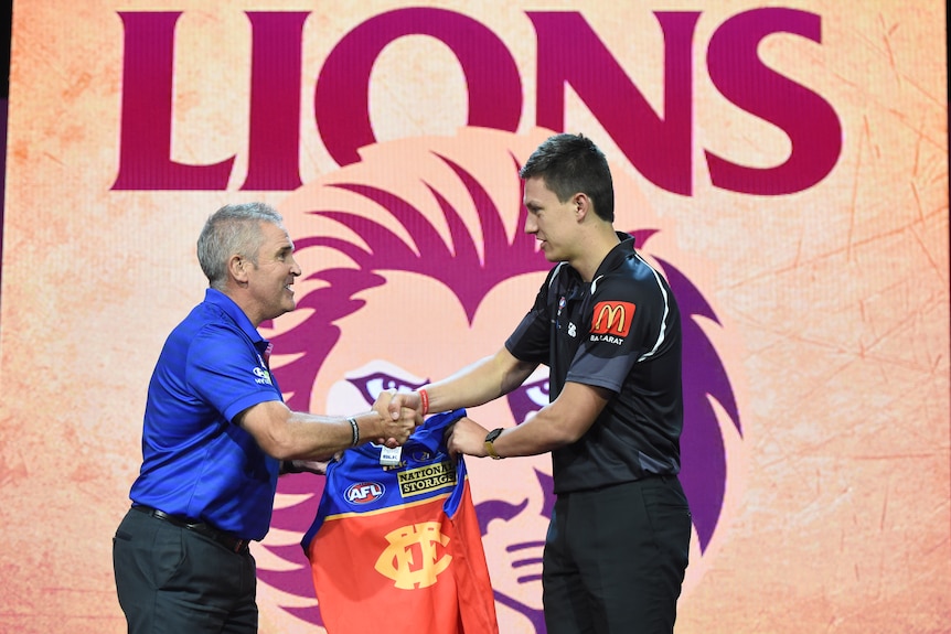 chris fagan shakes hands with number three draft pick hugh mcluggage while handing him his jumper