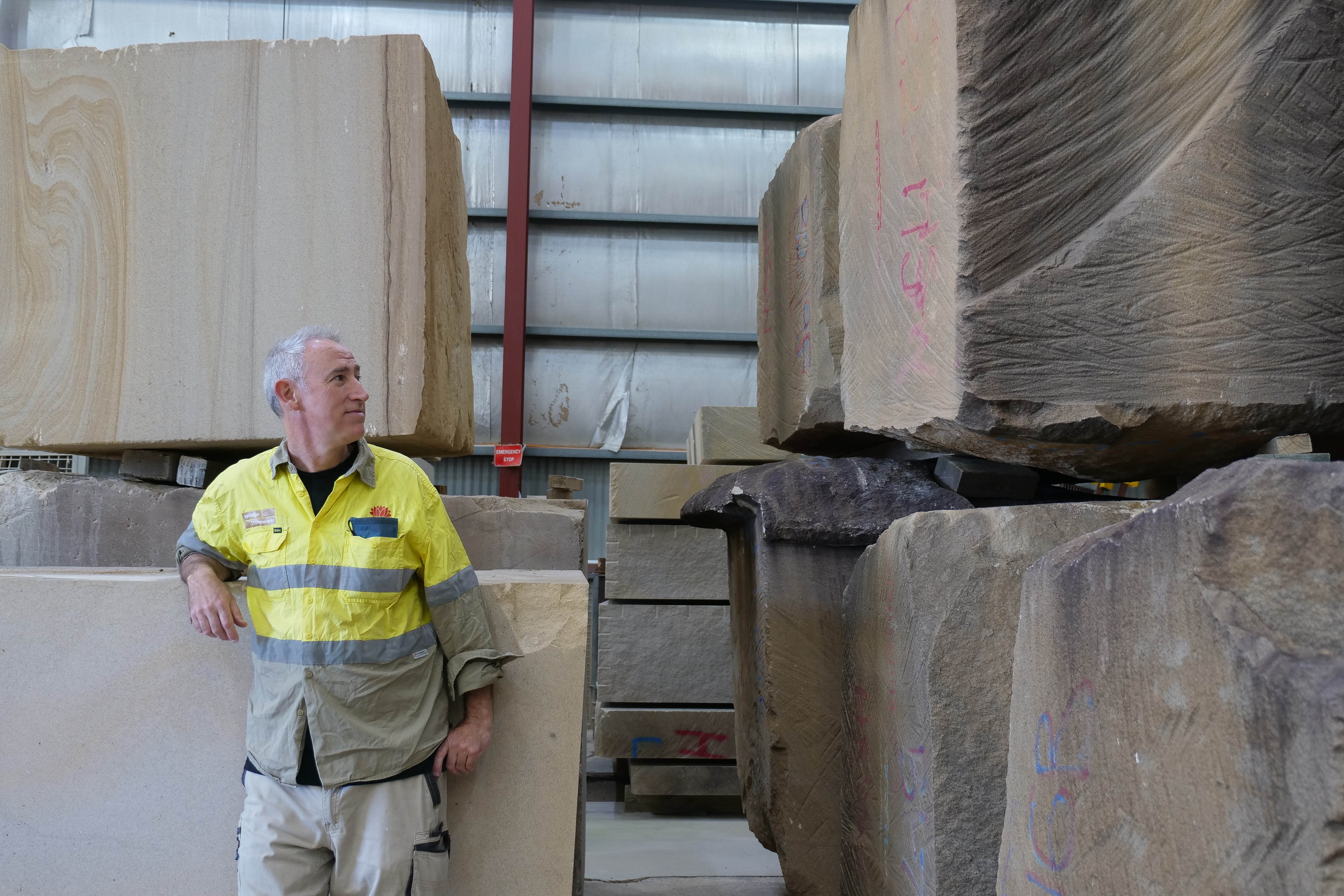 a man leans on a sandstone block next to other large blocks of sandstone