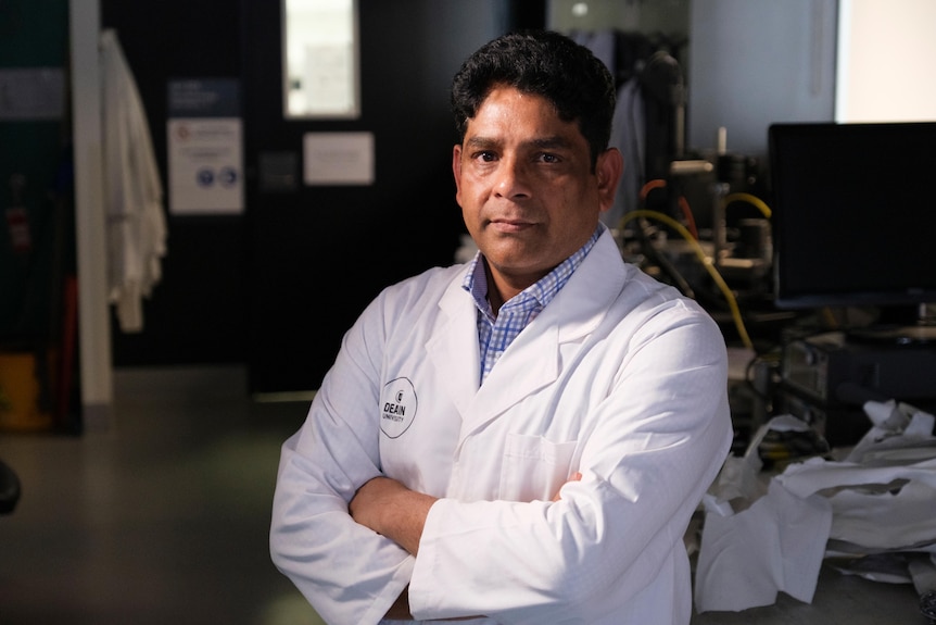 a man wearing a white lab suit standing in a science laboratory.