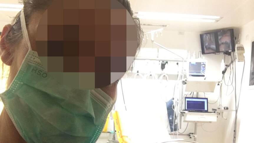 A doctor whose face is blurred, takes a selfie in a clinic room at a hospital in Austria.