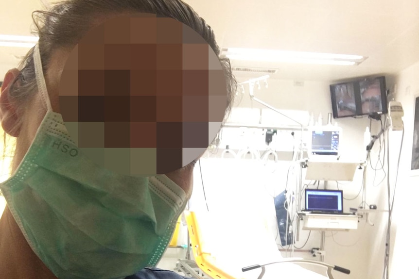A doctor whose face is blurred, takes a selfie in a clinic room at a hospital in Austria.