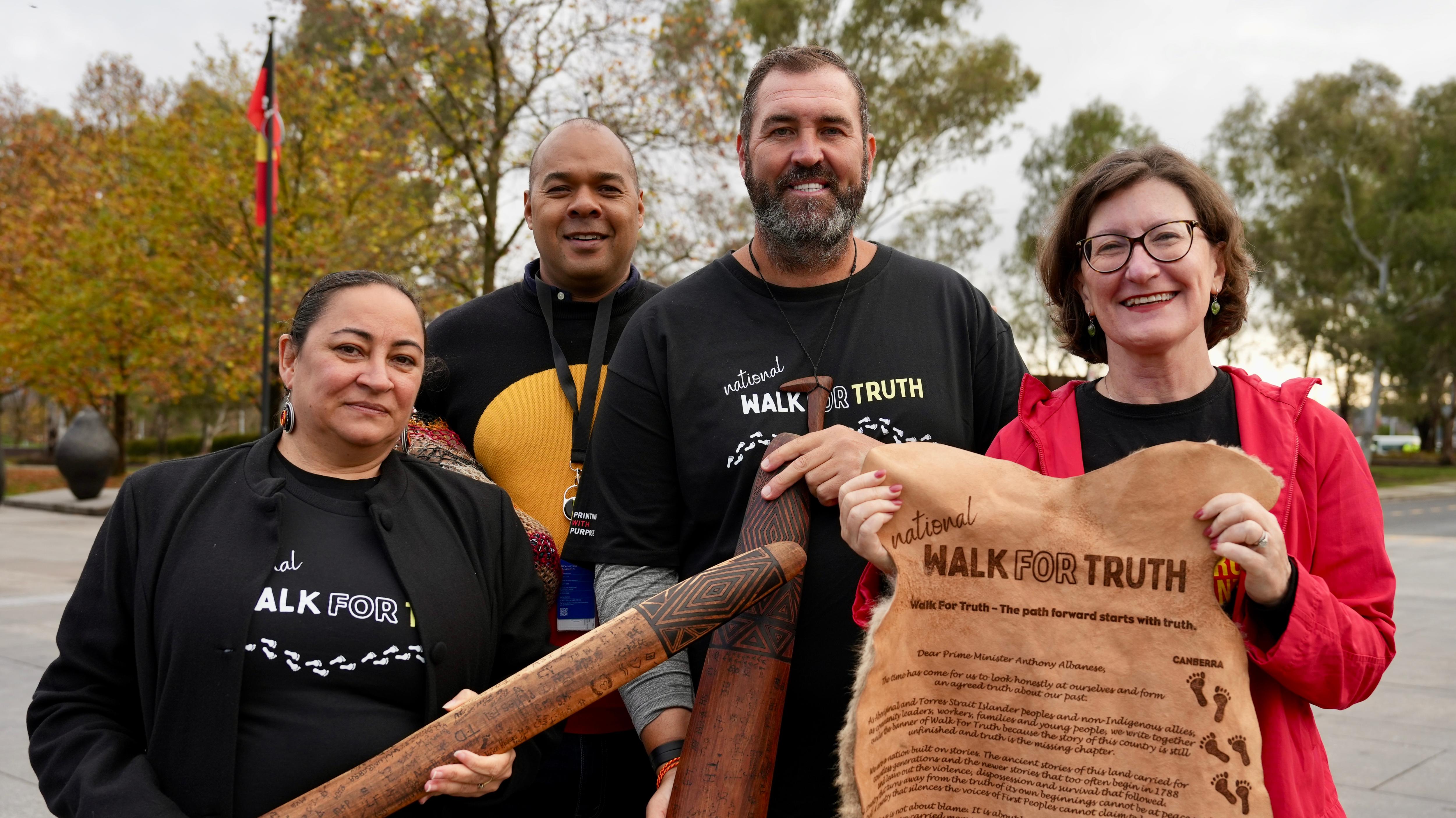 Two women and two men hold up Walk for Truth letter written on kangaroo skin
