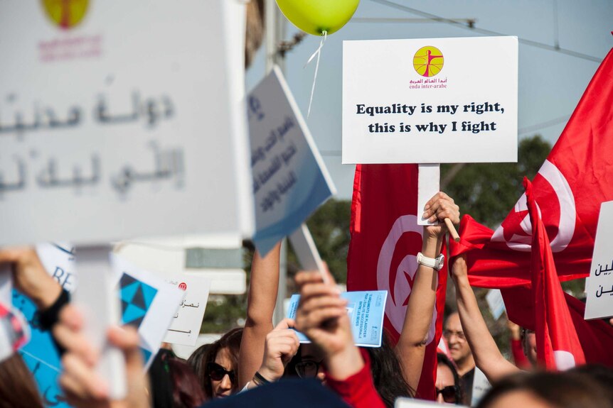 Tunisian women hold a placards during a protest