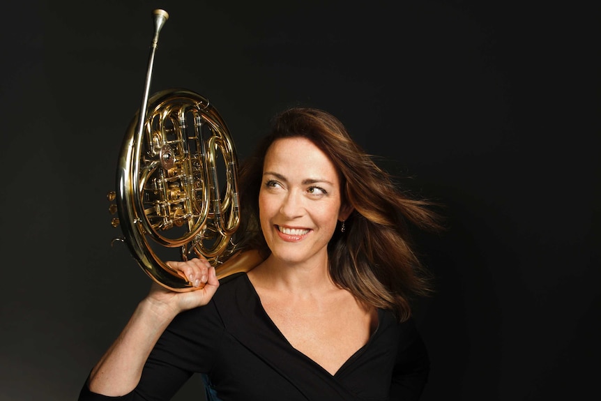 Horn player Sarah Willis holding her horn above her head